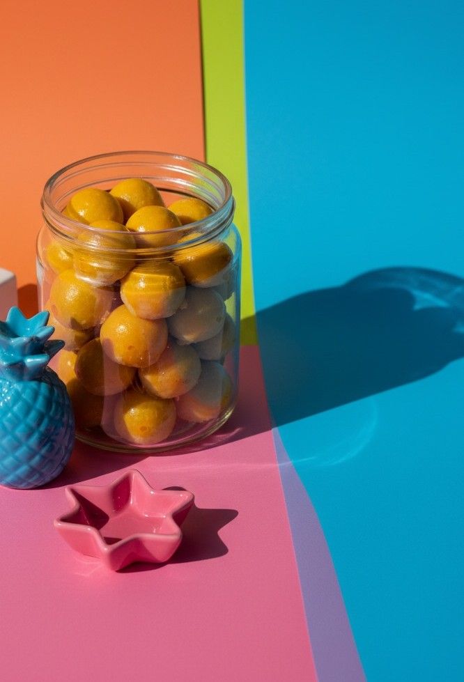 Toples kaca berisi Nastar di latar kertas warna-warni, kue faiha.id untuk snack time di kantor